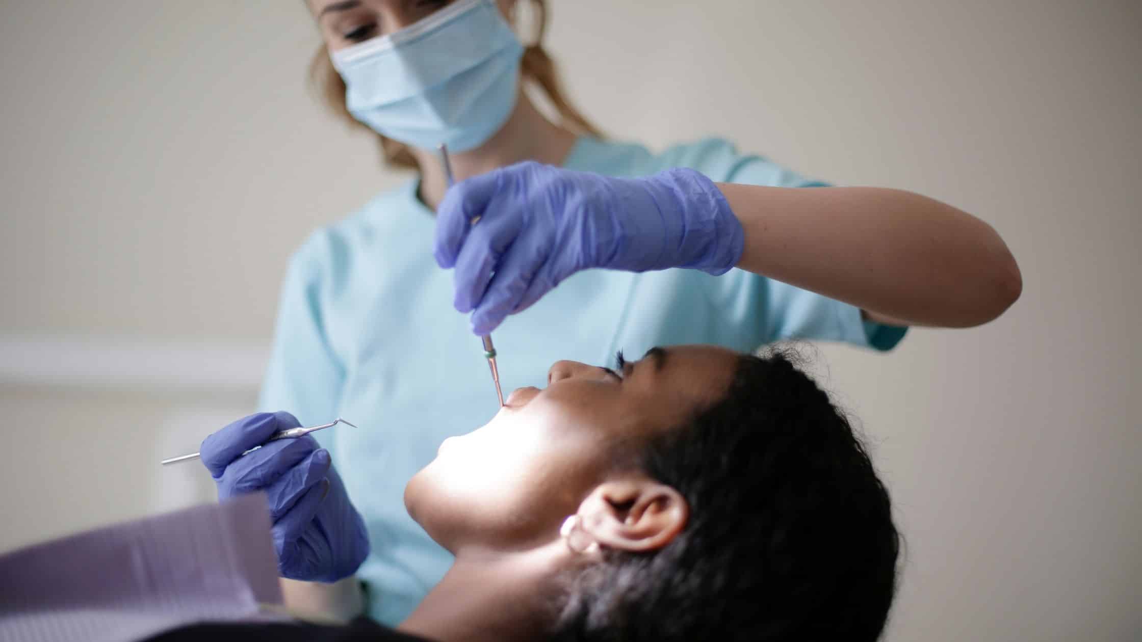 estetik dolgu uygulaması öncesi bir hasta ve diş çürüğü temizleyen bir doktor